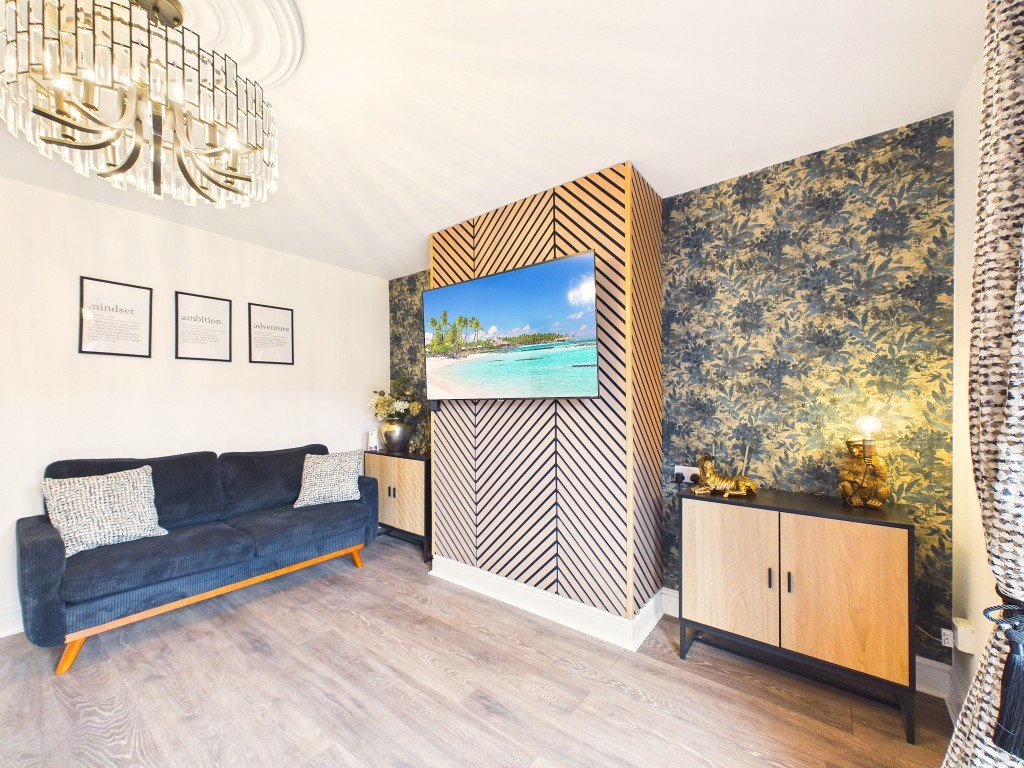 Modern living room with blue sofa, geometric wall art, TV display, and wooden flooring