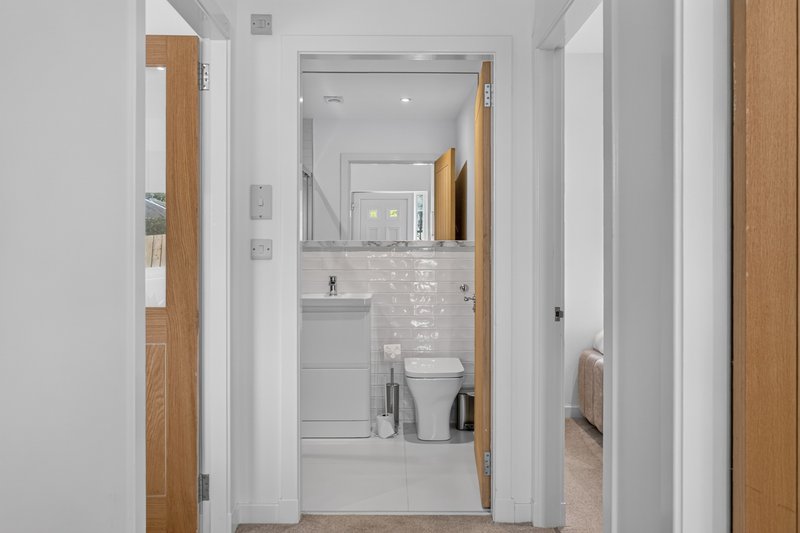 Modern bathroom with white subway tiles, mirror, toilet, sink and wooden door frame