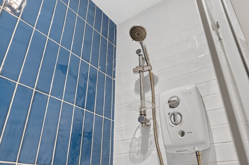 Bathroom shower area with blue tile wall and chrome showerhead fixture