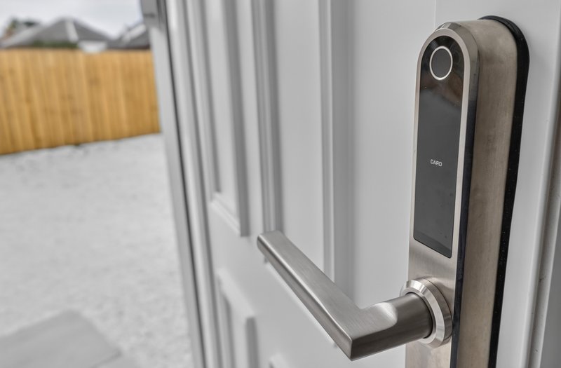 Modern smart door handle with electronic lock on white door frame