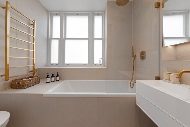Modern bathroom with freestanding bathtub, dual vanity sink, wooden towel rail and large windows