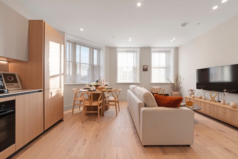 Open-plan living space with kitchen, dining area, sofa and TV, wooden flooring throughout