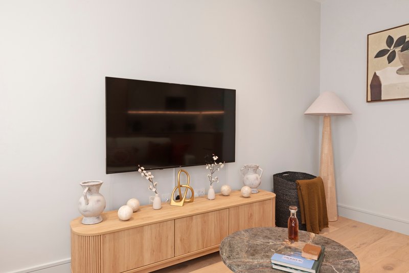 Living room with wall-mounted TV, wooden media console, decorative items and floor lamp
