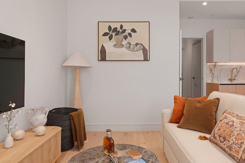 Modern living room with wooden furniture, sofa with orange cushions, wall art, and lamp