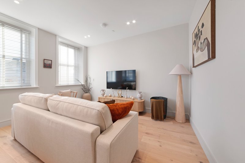 Modern living room with cream sofa, TV, wooden floor and large windows