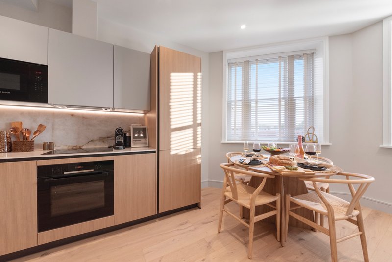 Modern kitchen and dining area with wooden cabinetry, dining table, and chairs
