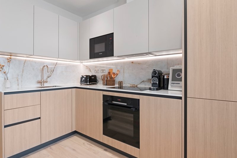 Modern kitchen with light wood and white cabinetry, marble backsplash, stainless steel appliances