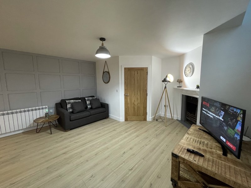 Spacious living room with black sofa, wooden flooring, flat-screen TV and fireplace