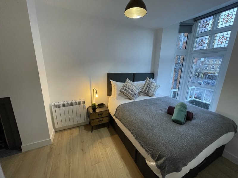 Modern bedroom with double bed, black headboard, wooden floor and pendant light