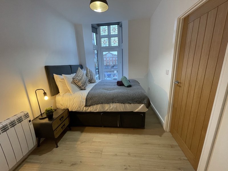 Compact bedroom with single bed, wooden floor, window and built-in wardrobe