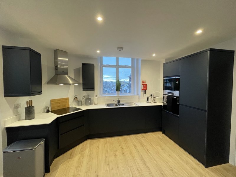 Modern kitchen with black cabinetry, white countertops, wooden flooring and large window with views