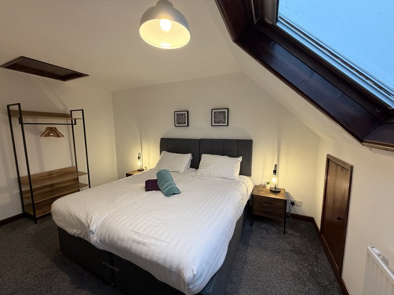 Attic bedroom with double bed, pendant light, skylight window and clothing rail