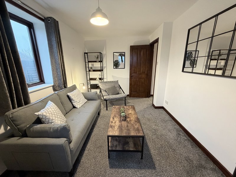 Modern living room with grey sofa, wooden coffee table, pendant light and large window