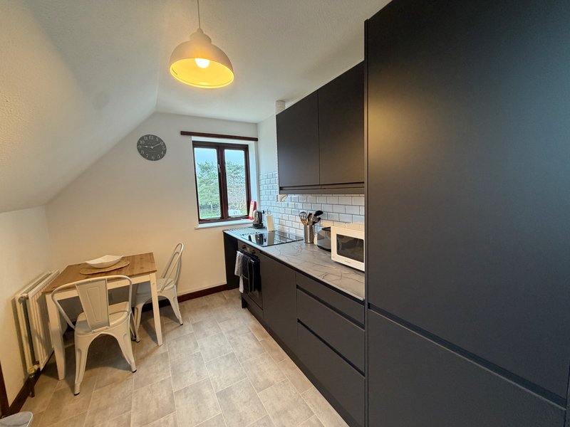Modern kitchen with dark cabinetry, white subway tiles, pendant light and dining table