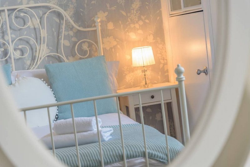 Bedroom with metal bed frame, blue cushion, bedside lamp and white wardrobe