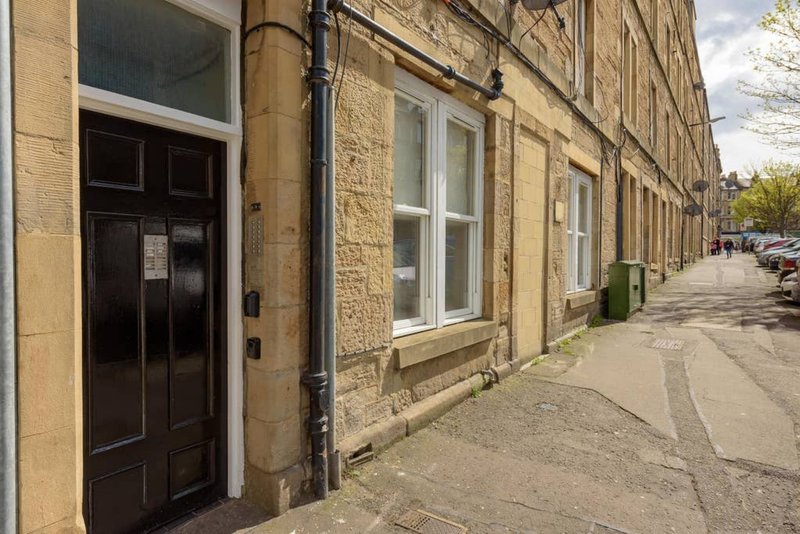 Stone terraced building exterior with black door, sash windows and street frontage