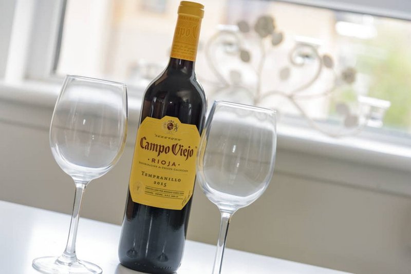 Wine bottle with gold foil wrap and two empty wine glasses on windowsill