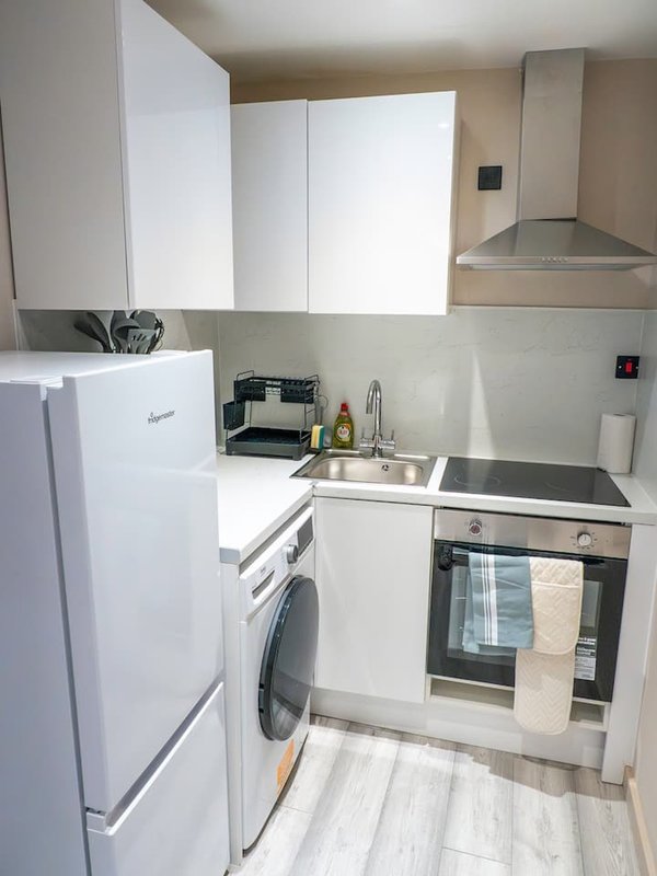 Compact kitchen with white appliances, washing machine, oven and extractor hood