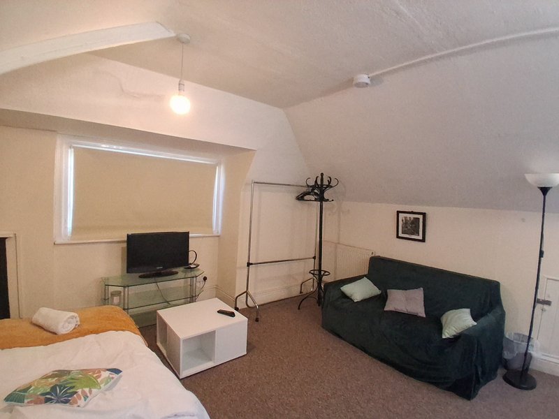 Attic bedroom with double bed, sofa, TV, and colorful cushions