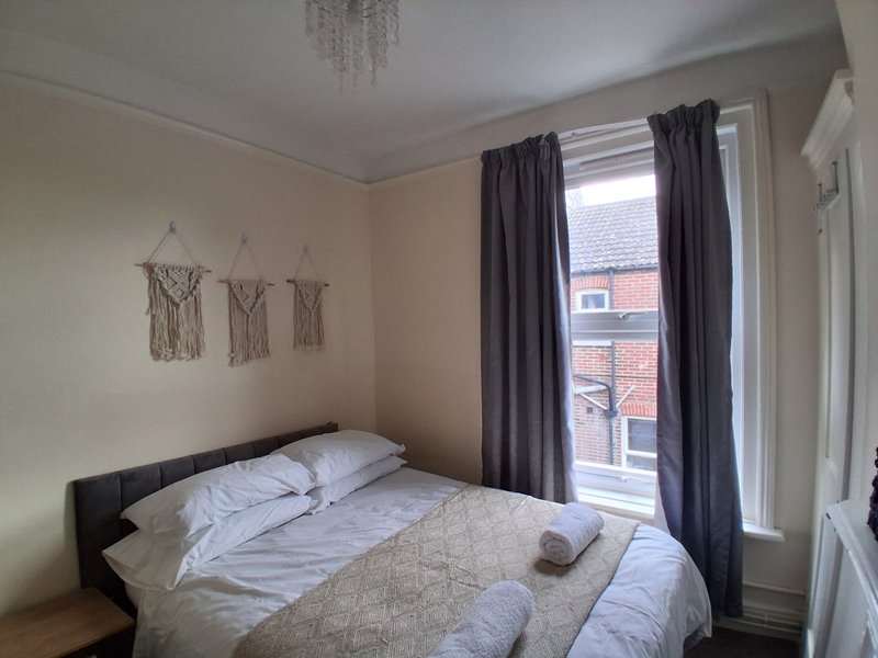 Bedroom with double bed, dark curtains, window with street view, and wall hangings