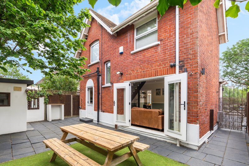 Red brick house exterior with patio, picnic table, and garden seating area