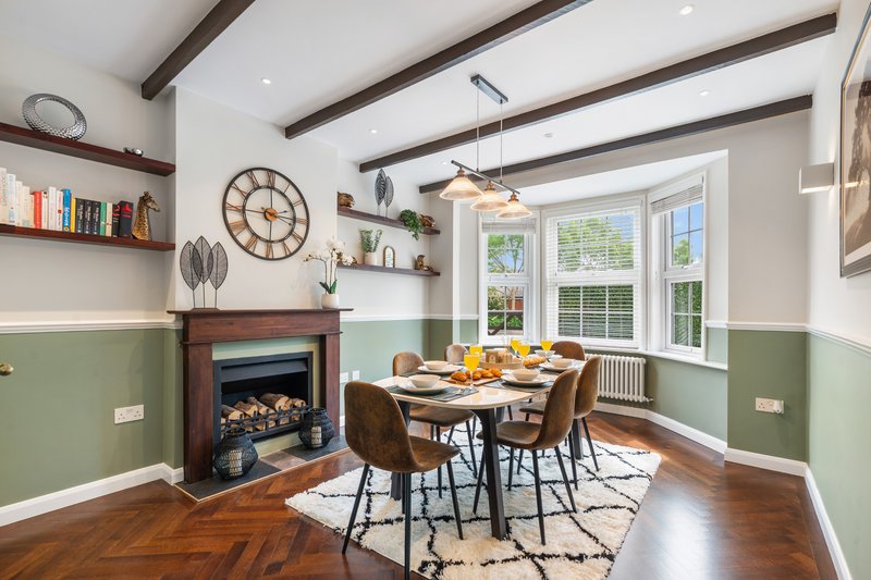 Modern dining room with fireplace, wooden beams, green wall paneling and large windows