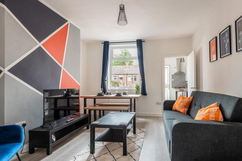 Modern living room with geometric wall art, sofa, TV unit, and window with blue curtains