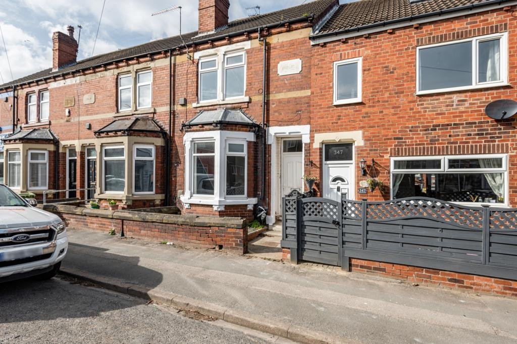 Red brick terraced house with bay windows, driveway and grey metal gates