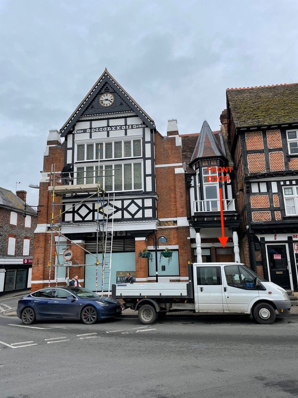 Tudor and brick period buildings with parked vehicles on street frontage