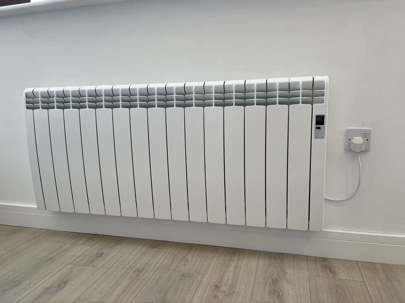 Modern white electric radiator mounted on wall with thermostat control