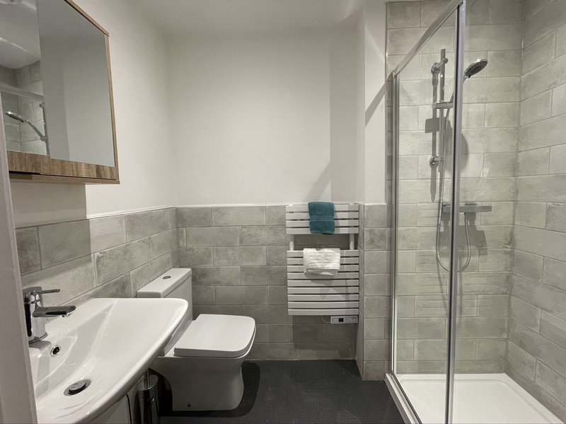 Modern bathroom with white sink, toilet, shower enclosure and heated towel rail