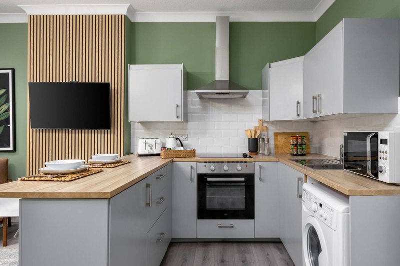 Modern kitchen with white cabinets, wooden countertops, stainless steel appliances and green walls