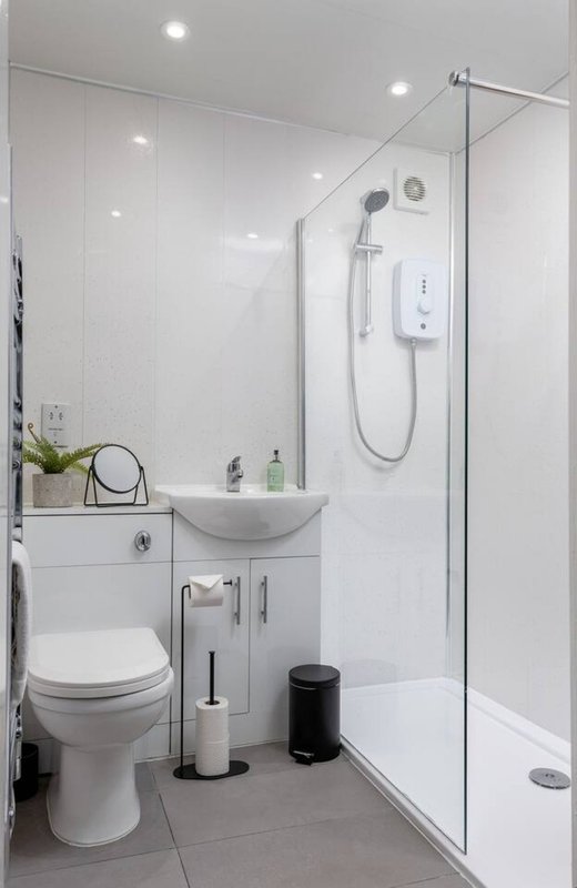 Modern bathroom with white vanity, toilet, shower enclosure and recessed lighting
