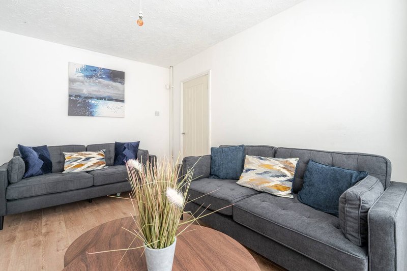 Living room with two grey sofas, wooden floor, decorative plant and framed artwork