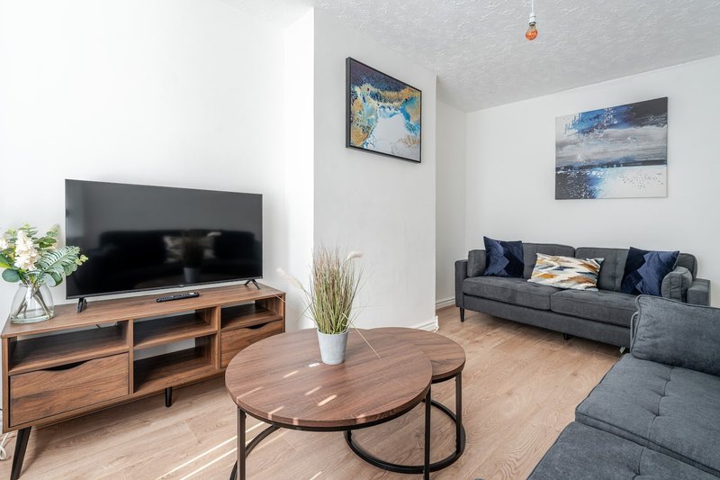 Modern living room with gray sofa, wooden TV stand, round coffee table and wall art