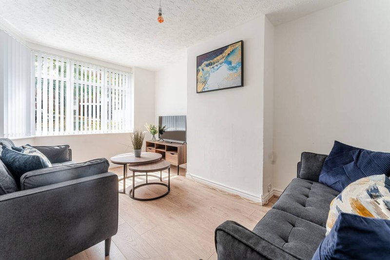 Bright living room with grey sofas, wooden floor, coffee table and framed artwork