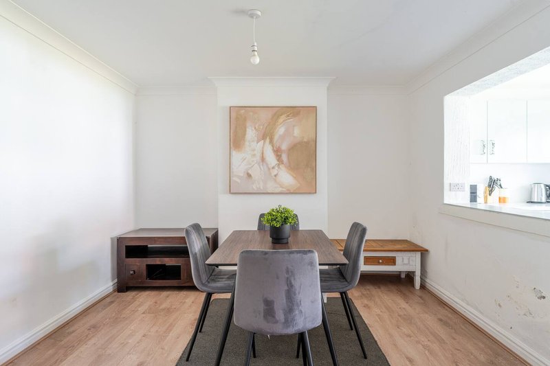 Bright dining room with wooden table, grey chairs, and framed artwork on wall