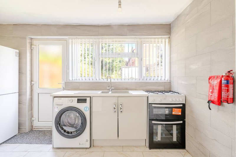 Kitchen with washing machine, sink, built-in oven, and window with vertical blinds
