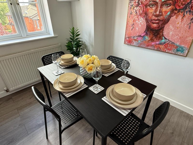 Modern dining room with black table, four chairs, place settings, yellow flowers and abstract wall art