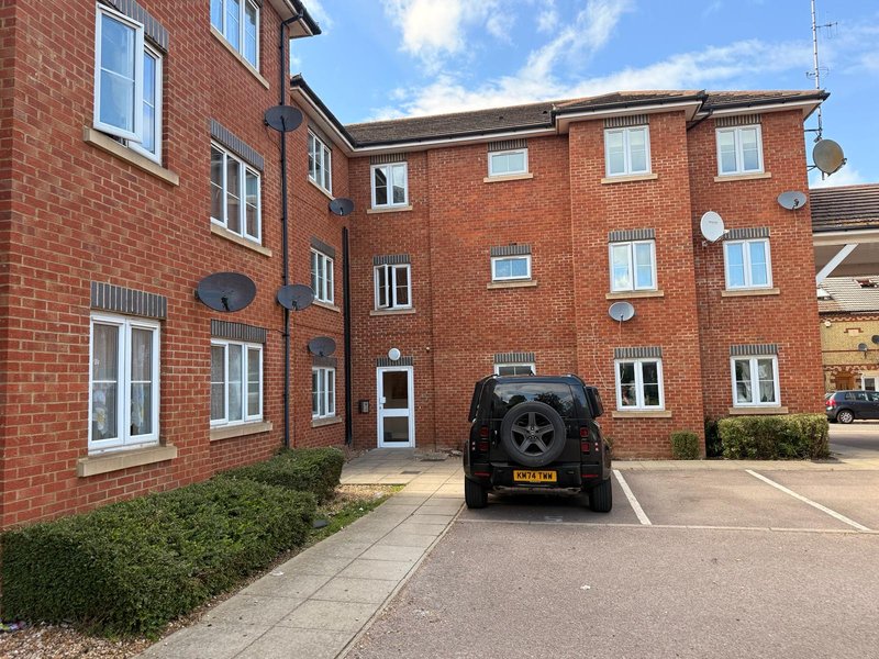 Red brick apartment building with parked car, driveway and entrance door
