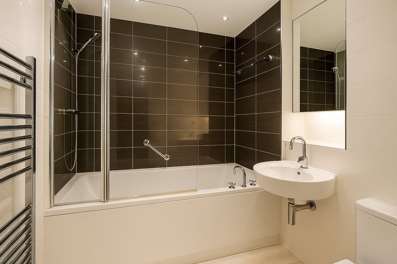 Modern bathroom with black tile shower enclosure, white basin, mirror and heated towel rail
