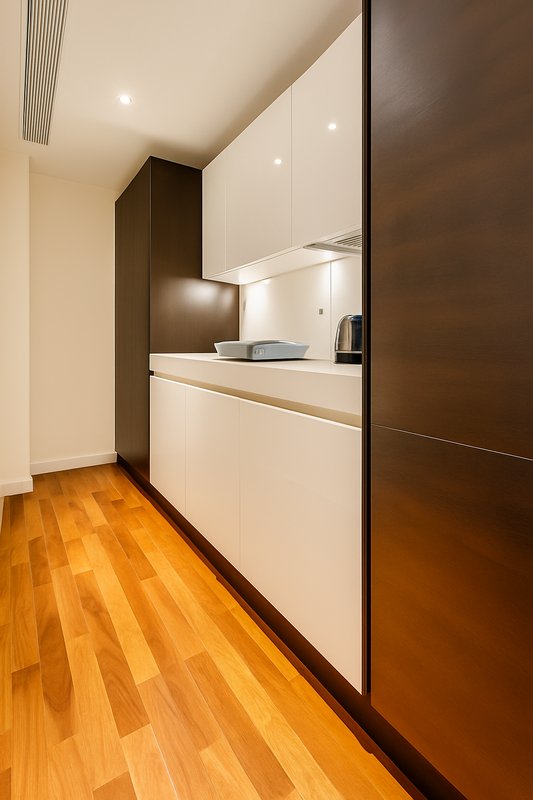 Modern kitchen with white cabinetry, wooden flooring, and integrated appliances