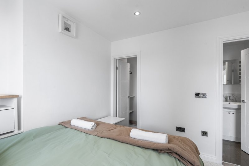 Modern bedroom with double bed, green bedding, wooden headboard, and ensuite bathroom door
