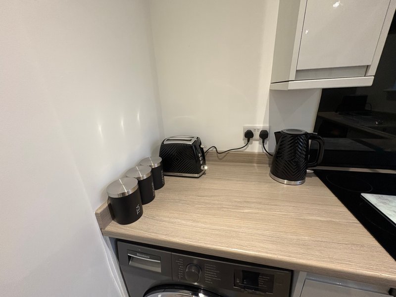 Kitchen counter with toaster, kettle, and small appliances on wood surface