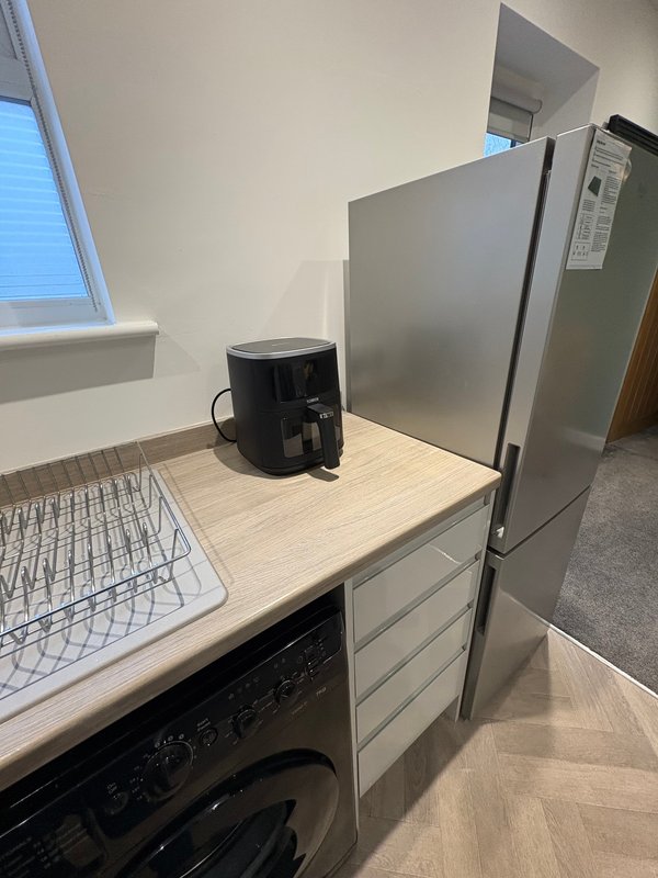 Kitchen counter with air fryer, refrigerator, and dishwasher in bright room