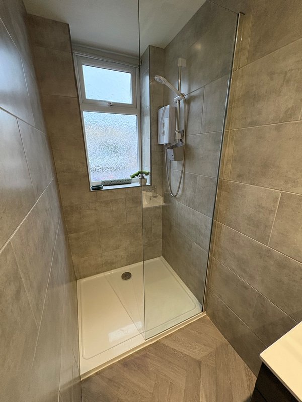 Modern bathroom with walk-in shower enclosure, tiled walls, window and heated towel rail
