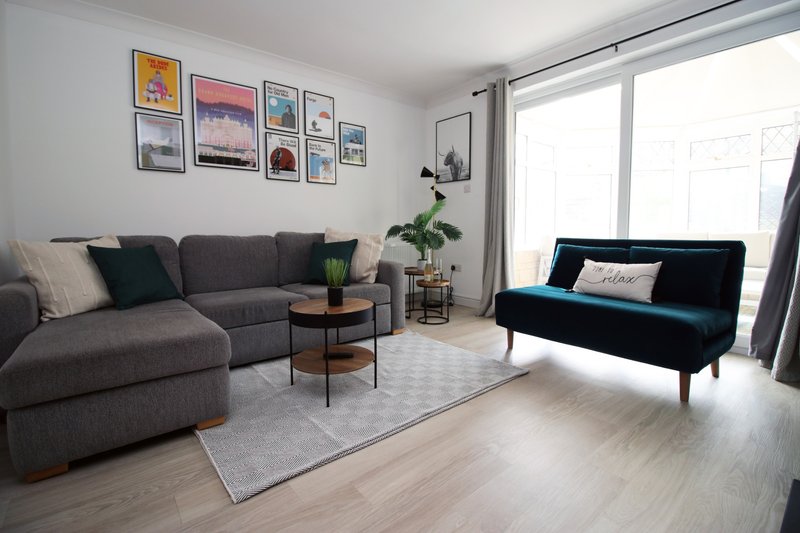 Bright living room with gray sectional sofa, teal armchair, wooden floor and framed wall art