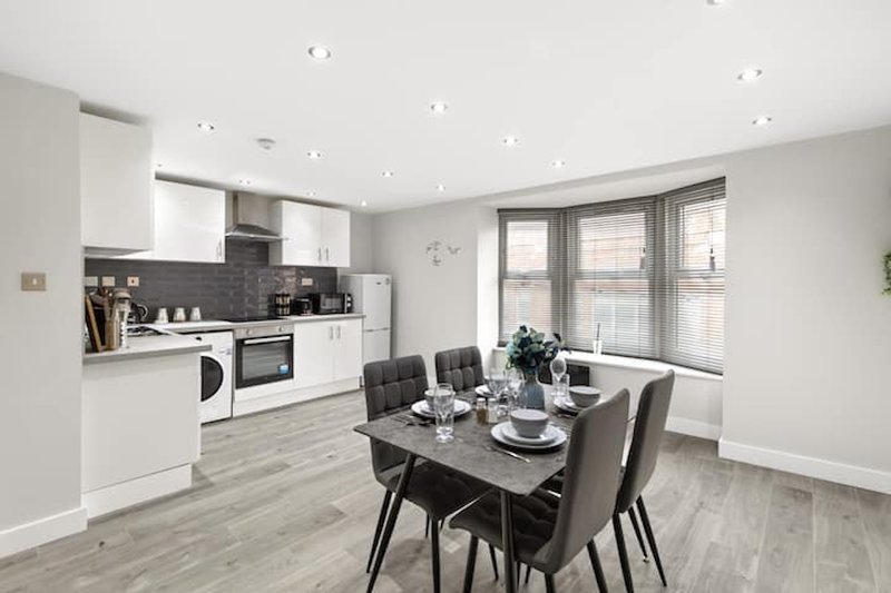 Modern open-plan kitchen and dining area with white cabinetry, dining table and chairs