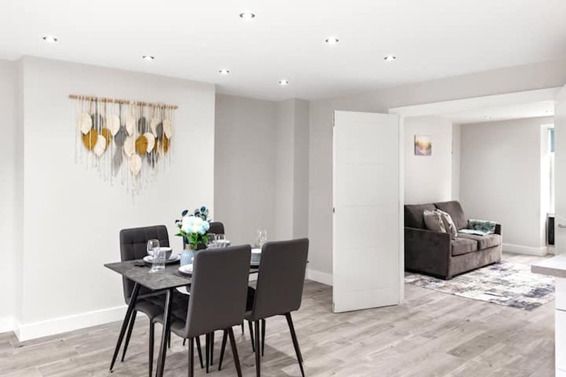 Open-plan dining and living area with dining table, chairs, pendant lighting fixture, and sofa visible