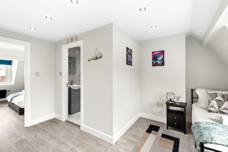Modern bedroom with twin beds, ensuite bathroom, wooden flooring and recessed ceiling lights